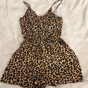 Leopardmönstrad jumpsuit med smala axelband - Trendig leopardmönstrad jumpsuit med smala axelband och elastisk midja. Lätt och bekväm. Ej blivit använd 