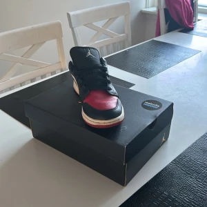 Nike Air Jordans i svart, röd och vit - Snygga Nike Air Jordans i klassisk svart, röd och vit färgkombination. Skorna har snörning och en ikonisk design med Nike-logga på sidan. Perfekta för dig som vill ha en stilren och sportig look.