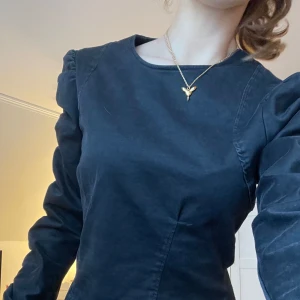 Svart jeans topp - Snygg svart långärmad jeans topp med rund halsringning och puffiga ärmar. Perfekt för en stilren look.