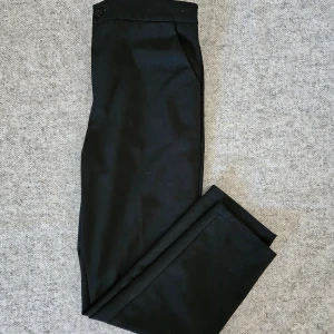 Svarta kostymbyxor i ankellängd  - Använd en del, så spår av användning finns men hela och rena. Dom är nästan i ankellängd på mig som är 159 CM. Märkt storlek S men resår i bak så kan säkert passa större och mindre också.