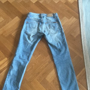 Blå jeans från Nudie - Snygga ljusblå jeans från Nudie med klassisk femficksdesign och broderad bakficka. Perfekta för en avslappnad stil. De har en rak passform och är tillverkade i slitstarkt denim. Pris kan diskuteras🙏