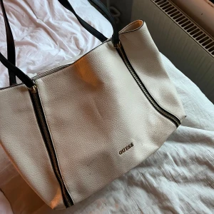 Beige/vit väska från Guess -  beige väska från Guess. Väskan har ett märke som syns på bild 2. Kanske går att få bort.🩷 
