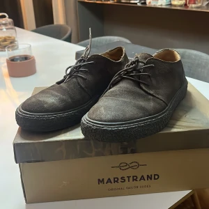 Bruna mockaskor från Marstrand - Snygga bruna mockaskor från Marstrand med snörning. Perfekta för en stilren look med en robust sula som ger bra grepp. Passar utmärkt till både vardag och mer uppklädda tillfällen.