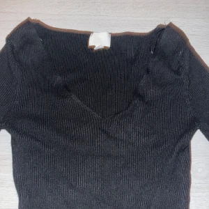 Svart ribbad långärmad tröja - Säljer den här svarta ribbade tröjan med slitt som man ser på andra bilden. Säljer pga den ej kommer till användning.