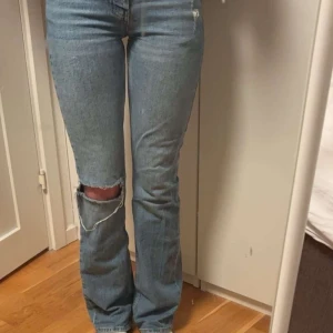 Blå bootcut jeans - Snygga blå bootcut jeans med hål på knäet. Jeansen är ursprungligen ifrån Gina i storlek 32. Jag som är 170cm så är längden perfekt men lite för små i midjan. Pris kan diskuteras.