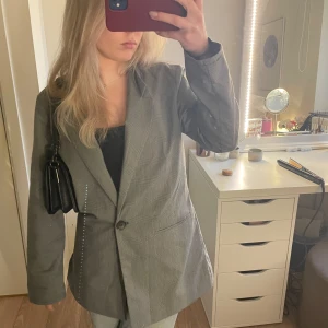 Grå kavaj - Säljer denna snygga grå kavajen med smått rutigt mönster. I nyskick och endast använd en gång. Passar perfekt till utgång och har snygg oversize passform. 