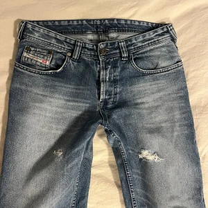 Jeans från diesel - Supersnygga, lågmidjade straight/flare jeans från Diesel. Snygga hål på benen. Står storlek 31 men passar ändå bra på mig som brukar ha 28 i waist. De är klippta och uppsydda så de är lagom på någon som är 160 och under. I bra skick! 