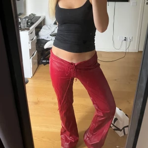 Röda byxor med snörning - Snygga röda byxor i syntetmaterial med snörning i midjan. Perfekta för en trendig look. hör av er vid intresse💕