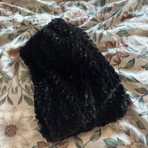 Svart fluffig halsduk - Mysig och varm svart halsduk med fluffig textur. Perfekt för kyliga dagar när du vill hålla dig varm och stilren. Denna halsduk är ett måste för vinterns garderob.