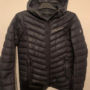 Svart dunjacka från Peak Performance - Storlek S. Väldigt lite använd. Finns ett litet litet millimetershål som man lätt kan limma igen om man vill. 