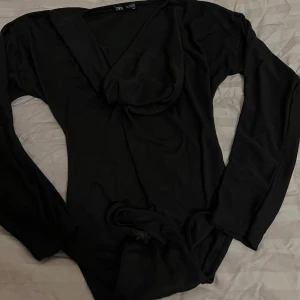 Svart långärmad topp från Zara - Snygg svart långärmad topp från Zara med draperad halsringning. Perfekt för en stilren look. Materialet känns mjukt och bekvämt mot huden. Som ny, inga deffekter eller skador. Finns även i mörkgrönt. 