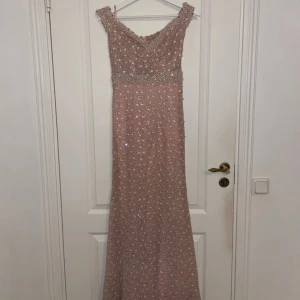 Glittrig rosa långklänning - Säljer en fantastisk glittrig rosa långklänning med v-ringad design och axelbandslös stil. Klänningen har en elegant passform och är perfekt för speciella tillfällen. Den är dekorerad med paljetter som ger en extra touch av glamour. Dragkedja i ryggen för enkel påklädning. Perfekt för att glänsa på festen! ✨