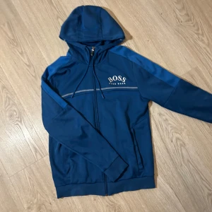 Blå huvtröja från Boss - Säljer en blå huvtröja från boss från de äldre modellerna, grymt skick inga märken, storlek s, sitter som den ska. Slutsåld överallt