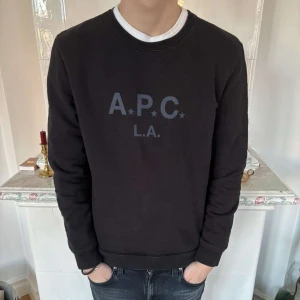 Svart sweatshirt från A.P.C. - Säljer en stilren svart sweatshirt från A.P.C. med tryck på framsidan. Perfekt för en avslappnad stil.