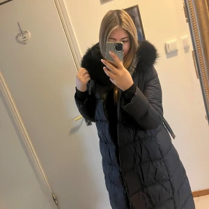 Svart feminina jacka  - Säljer en lång svart dunjacka med äkta päls, Jackan har en stilren design, perfekt för kyliga dagar. Har haft den sen förra vintern fint skick är ej rökare. Har två nya vinter jackor så den kommer inte till användning, passar till allt jätte classy o fin först till kvarn 🤍🫶🏽