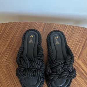 Svarta sandaler från H&M - Snygga svarta sandaler från H&M med flätad design. Perfekta för en avslappnad stil. Sandalerna har en bekväm sula och är lätta att bära. Storlek 38