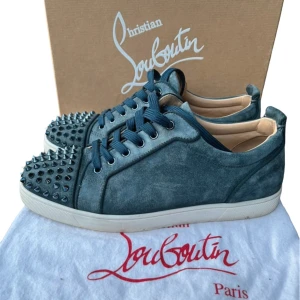 Christian Louboutin  - Snygga blå sneakers i mocka från Christian Louboutin med coola nitar på tån och klassisk röd sula. Skorna har snörning och en stilren design som sticker ut. Skriv om ni är sugna mvh scandicfashion skulle säga att dom sitter som 