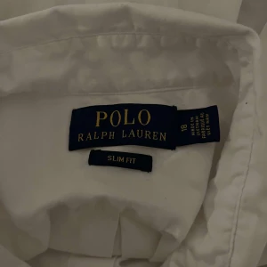 Vit skjorta från Polo Ralph Lauren - Säljer en klassisk vit skjorta från Polo Ralph Lauren i slim fit. Skjortan har långa ärmar och knappar framtill samt en broderad logotyp på bröstet. Perfekt för en stilren look. Pris kan diskuteras. Den är använd ett par gånger. Lite  större än S