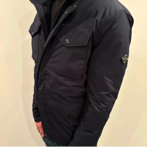 J.Lindeberg Field Jacket - Säljer denna stilrena field jacketen för endast 2200! Jackan är i ny skick och nypris ligger på runt 5-6 tusen. Jackan har både knappar och dragkedja. Jackan har flera fickor med lock och knappar, samt en hög krage för extra skydd. Perfekt för kyligare dagar.