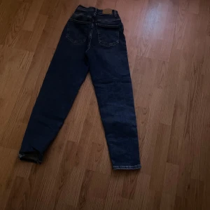Mörkblå skinny jeans med hög midja - Snygga mörkblå jeans med hög midja och smal passform. Klassisk femficksmodell med raka bakfickor och knappstängning fram. Jeansen är tillverkade i ett robust denimtyg och har en stilren look som passar till det mesta.