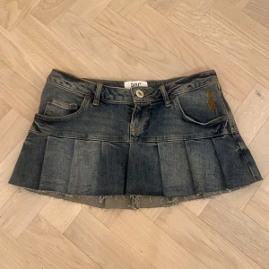 Jeanskjol från BDG Urban Outfitters - Snygg jeanskjol från BDG Urban Outfitters i en klassisk blå denim. Kjolen har en kort längd med plisserade detaljer och rå kant. Perfekt till sommaren! Ps, Står EJ för fraktens strul.