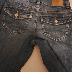 Blå jeans med knappar - Snygga blå jeans från gina tricot med knappar på bakfickorna.