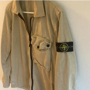 Beige jacka från Stone Island - Tjena, säljer nu denna snygga beiga stone island field jackan. Den är i storlek M men sitter lite mer åt small hållet, den är alltså lite liten i storleken. Den är i väldigt bra skick 9/10, materialet är väldigt tåligt och håller vinden ute. Perfekt till dig som vill ha något över din tjocktröja till våren/hösten. Pm för mer frågor👌🏻🍾 