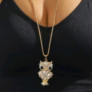 Guldigt halsband med uggla - Säljer ett supercoolt guldigt halsband med en glittrig uggla som hänge. Kedjan är 76 cm lång och ugglan är täckt med gnistrande stenar som verkligen fångar ljuset. Perfekt för att ge din outfit en unik touch! 🦉✨