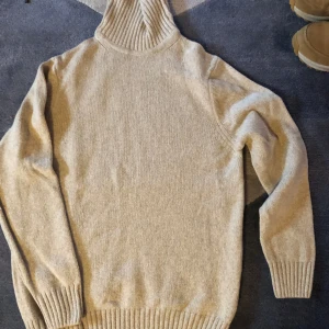 Beige stickad polotröja - Säljer en supermysig beige stickad polotröja. Perfekt för kalla dagar med sin höga krage och långa ärmar. Tröjan har ribbade muddar vid ärmslut och nederkant för extra komfort. Passar perfekt till både vardag och mysiga hemmakvällar. 🧶
