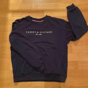 Mörkblå sweatshirt från Tommy Hilfiger - Säljer en snygg mörkblå sweatshirt från Tommy Hilfiger. Inte använd så mycket eftersom jag växte ur den snabbt. Bra skick! Köpt på NK i Stockholm. Passar till både jeans och chinos för en avslappnad stil.