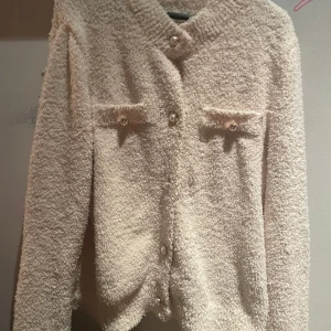 beige fluffig kofta med pärlknappar - Supermysig beige kofta i fluffigt material med fina pärlknappar.