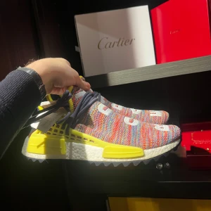 Färgglada sneakers från Adidas - Säljer ett par unika och färgglada Adidas sneakers i mycket bra skick. Skorna har en stickad ovandel i flera färger med texten 'BODH' och 'EARTH'. De har en vit sula med gula detaljer och mörkblå snörning. Perfekta för att sticka ut i mängden!