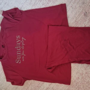 Röd pyjamas från Shein - Säljer en röd pyjamas från Shein med texten 'Sundays are for sleeping' tryckt på framsidan. Den är kortärmad och perfekt för en avslappnad stil. Pjyamas är i bra skick och gjord av mjukt material. Perfekt för en chill dag hemma eller en casual utflykt.