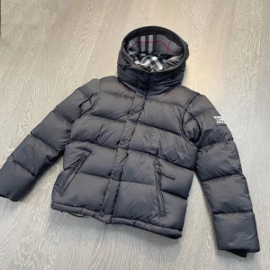 Burberry Jacka - Tja, Säljer en svart Burberry jackan som passar perfekt inför vintern nu. Storlek M på jackan. Jackan är fällbar till en väst då man kan använda den på hösten och sommaren om man vill det. Priset är inte hugget i en sten. Jackan är i väldigt bra skick.