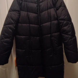 Svart lång dunjacka - Säljer en svart lång pufferjacka mycket bra skick. Perfekt för kalla vinterdagar. jackan har en dragkedja framtill och är supervarm och mysig. Passar perfekt för alla outfits