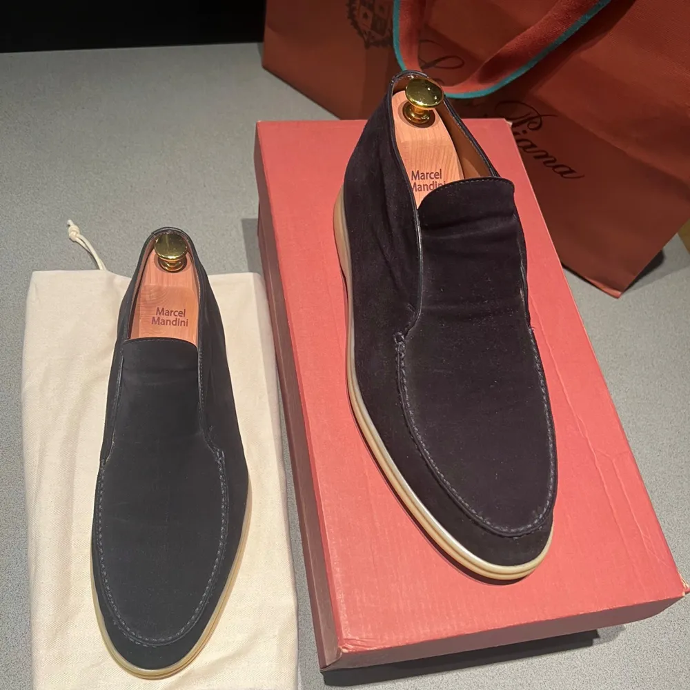 Säljer ett par eleganta svarta loafers i mocka från Loro Piana. De har en stilren design med ljus sula och är perfekta för både vardag och fest. Skorna är i mycket bra skick och kommer med originalförpackning.. Skor.