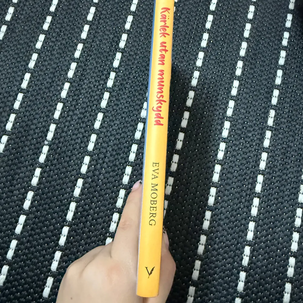 Boken 'Kärlek utan munskydd' av Eva Moberg är en roman som utspelar sig under pandemin. Den handlar om tre singlar och deras liv under tre månader i Norrköping. Omslaget visar en solig stadsmiljö med en kvinna som går över en bro. Perfekt för dig som gillar samtida berättelser med en twist av romantik och humor!. Böcker.