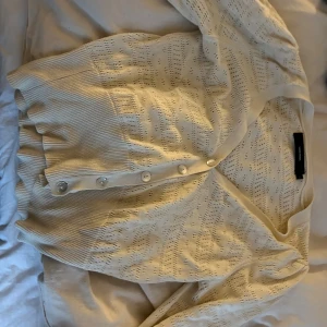 Beige kofta från vero Moda  - Säljer en superfin beige kofta från vero Moda  i mycket bra skick. Den är stickad med ett diskret mönster och har knappar framtill. Perfekt för höst och vår, och den är långärmad vilket gör den mysig och varm. Passar till både vardag och fest!