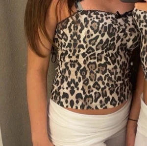 Leopardmönstrad linne - Säljer en snygg leopardmönstrad linne från Gina Tricot med spetsdetaljer vid halsringningen. Toppen har smala axelband och en liten rosett framtill. Perfekt för en utekväll eller sommarfest! 🐆✨