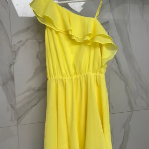 Gul klänning från Bik Bok - Säljer en superfin gul klänning från Bik Bok i storlek S. Den har en one-shoulder design med volangdetaljer och är perfekt för sommarens fester. Klänningen är i ett lätt och luftigt material som gör den bekväm att bära hela dagen.