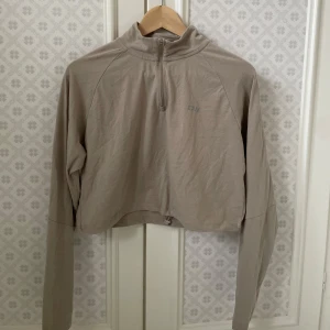 Beige tröja från ICIW - Säljer en snygg beige tröja från ICIW i storlek M. Den har en halv dragkedja framtill och är perfekt för både träning och vardag. Materialet känns mjukt och bekvämt, och den har långa ärmar för extra värme. Perfekt för höst och vår!