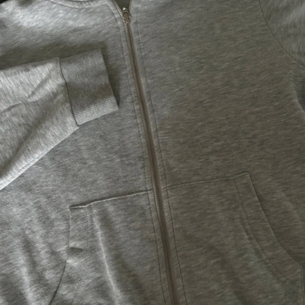 Säljer en grå hoodie i mycket bra skick. Den har en dragkedja framtill och en mysig huva. Perfekt för höst och vår, och passar till alla casual outfits. Storleken är normal och materialet känns mjukt och bekvämt. . Tröjor & Koftor.