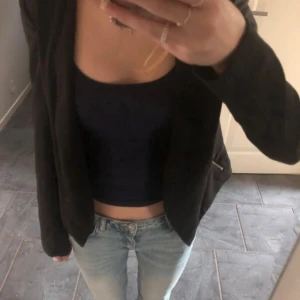 Svart kavaj från Vero Moda - Snygg svart kavaj från devided i bra skick. Perfekt för både vardag och fest! Den har en öppen design utan knappar och dragkedjedetaljer på sidorna. Passar till jeans eller klänning för en stilren look💗