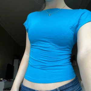 Blå offshoulder topp - Säljer en snygg blå offshoulder topp i tight passform. Toppen är ärmlös och har en öppen rygg, perfekt för sommardagar eller festliga tillfällen. Materialet är mjukt och stretchigt, vilket gör den bekväm att bära hela dagen!💙