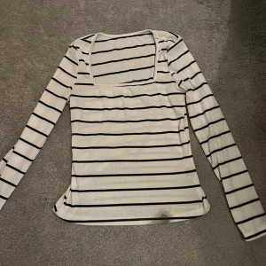 Randig långärmad topp från SHEIN - Säljer en randig långärmad topp från SHEIN i svart och vit. Toppen har en fyrkantig halsringning och är ribbad i materialet. Den är i bra skick men har en liten fläck längst ner. Perfekt för vardagsbruk eller en avslappnad dag ute.