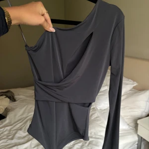 Grå oneshoulder body från Gina Tricot - Snygg grå oneshoulder body från Gina Tricot i nytt skick. Perfekt för festliga tillfällen med sin unika design och cutout-detalj. Materialet är mjukt och stretchigt för en bekväm passform. Helt oanvänd och prislapp kvar, nypris 299 kr 🩶