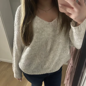 Vit stickad tröja - Mysig vit stickad tröja med v-ringning och långa ärmar. Perfekt för kyliga dagar och ger en avslappnad look. Passar bra till jeans eller kjol för en casual stil.