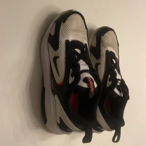 Nike Air Max Bolt - Säljer ett par Nike Air Max sneakers i svart och vitt med röda detaljer. Perfekta för både vardag och träning. Storlek 35. Bra skick