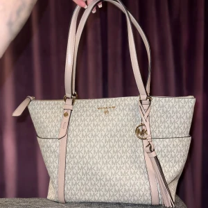 Michael kors väska  - Säljer min fina Michael Kors väska med rosa detaljer som är använd väldigt fåtal gånger.  massa olika fickor innuti. 