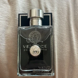 Versace Pour Homme Eau de Toilette - Säljer en elegant och stilren Versace Pour Homme Eau de Toilette. Flaskan är genomskinlig med en silverfärgad kork och har Versaces ikoniska medusamärke på framsidan. Parfymen är 100 ml och kommer i en snygg svart kartong med gulddetaljer. Perfekt för den som vill dofta lyxigt och fräscht! Säljer sampels på 5 ML